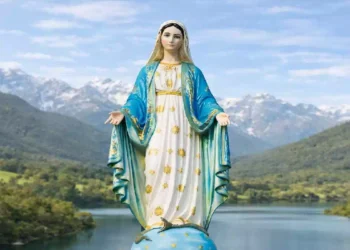 Statua della Vergine Maria con manto azzurro e veste bianca decorata da stelle dorate, in piedi su un globo davanti a un paesaggio di colline verdi