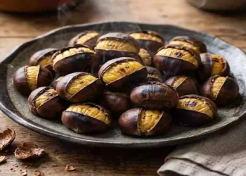 Castagne arrostite fumanti servite in un piatto rustico di ceramica su tavolo in legno, simbolo dei sapori autentici dell’autunno e della tradizione culinaria italiana.