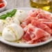 Mozzarella e prosciutto serviti in estate su piatto fresco