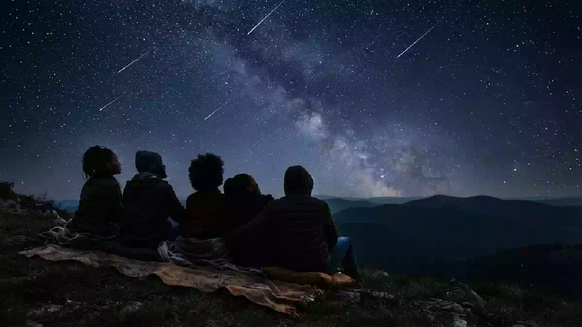 Notte stellata con scie luminose di stelle cadenti osservate da una persona che pensa al desiderio da esprimere secondo il proprio segno zodiacale.