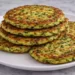 Frittelle di zucchine al forno dorate e croccanti servite su piatto bianco, antipasto leggero senza olio
