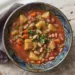 Foto di uno spezzatino vegetale con fagioli rossi, patate e peperoni in salsa cremosa, servito caldo in una ciotola rustica.
