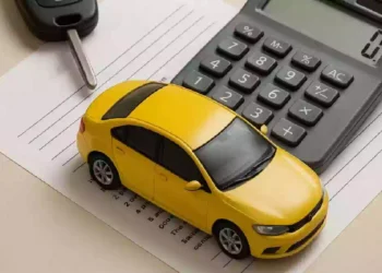 Modellino di auto gialla accanto a una calcolatrice e a una chiave dell’automobile su documenti amministrativi, simbolo del pagamento del bollo auto, delle tasse automobilistiche e delle scadenze fiscali dei veicoli.