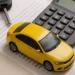 Modellino di auto gialla accanto a una calcolatrice e a una chiave dell’automobile su documenti amministrativi, simbolo del pagamento del bollo auto, delle tasse automobilistiche e delle scadenze fiscali dei veicoli.