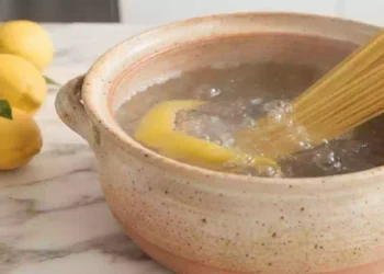 Piatto di pasta appena scolata con limone fresco accanto, simbolo del trucco per evitare che la pasta si attacchi durante la cottura.
