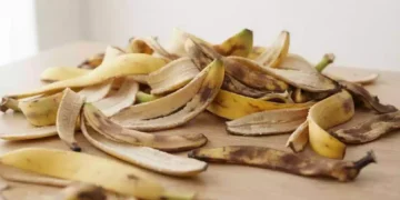 Vasetto di fertilizzante naturale ottenuto frullando bucce di banana in acqua, posato accanto a piante da appartamento per mostrare il rimedio domestico utile alla loro cura.