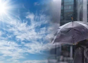 Contrasto meteorologico di fine settembre con sole splendente e cielo sereno da un lato, pioggia intensa e ombrello sotto un temporale urbano