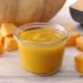 Pesto di zucca fatto in casa in vasetto di vetro con cubetti di zucca fresca su tagliere di legno, ideale per condire pasta, risotti e bruschette autunnali.
