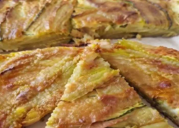 Pizza di fiori di zucca senza impasto cotta in padella, con mozzarella filante e superficie dorata e croccante, tagliata a spicchi e servita calda.