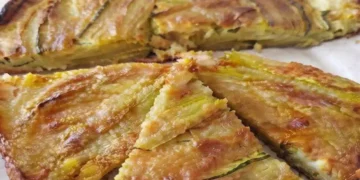 Pizza di fiori di zucca senza impasto cotta in padella, con mozzarella filante e superficie dorata e croccante, tagliata a spicchi e servita calda.