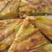 Pizza di fiori di zucca senza impasto cotta in padella, con mozzarella filante e superficie dorata e croccante, tagliata a spicchi e servita calda.