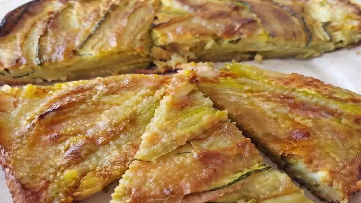 Pizza di fiori di zucca senza impasto cotta in padella, con mozzarella filante e superficie dorata e croccante, tagliata a spicchi e servita calda.