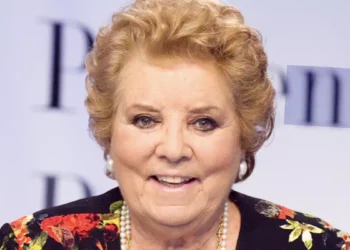 itratto ravvicinato di Wilma De Angelis durante un evento pubblico, con giacca a fantasia floreale, collana di perle e sfondo chiaro sfocato