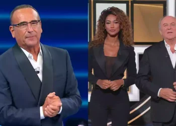 Carlo Conti in studio per Tale e Quale Show accanto a una schermata con Gerry Scotti e una concorrente de La Ruota dei Campioni e delle Stelle