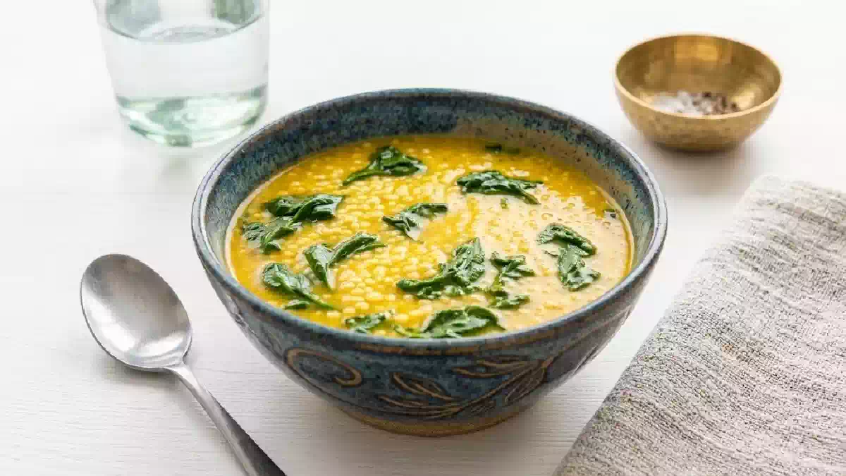 Fregola con crema di ceci e cavolo nero servita in una ciotola rustica, primo piatto invernale ricco di fibre e proteine vegetali, ideale per una dieta sana e nutriente