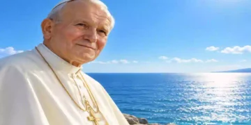 San Giovanni Paolo II in primo piano davanti al mare azzurro e scintillante, con cielo limpido e luce solare intensa all’orizzonte. Ritratto luminoso e realistico del Pontefice in abito bianco