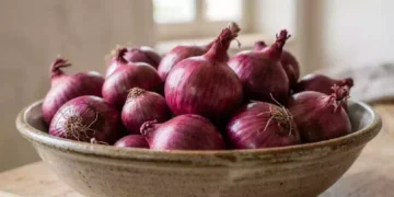 Cipolle rosse fresche disposte in una ciotola di terracotta su un tavolo in legno, protagoniste di un rito popolare legato alla fortuna e alle tradizioni domestiche