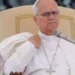 Papa Leone XIV durante un intervento pubblico in Vaticano, seduto su una poltrona chiara e con un microfono davanti, mentre parla ai fedeli in occasione dell'Angelus