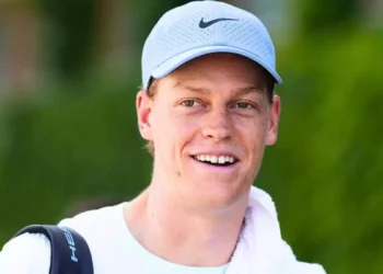 Jannik Sinner in primo piano con cappellino chiaro durante un torneo di tennis, dopo l'annuncio dello stop alla stagione 2026 per curare il problema al ginocchio