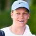 Jannik Sinner in primo piano con cappellino chiaro durante un torneo di tennis, dopo l'annuncio dello stop alla stagione 2026 per curare il problema al ginocchio