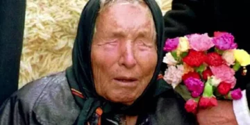 Baba Vanga durante un'apparizione pubblica, ritratta con un foulard nero sul capo e un mazzo di fiori colorati accanto, simbolo delle celebri profezie