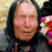 Baba Vanga durante un'apparizione pubblica, ritratta con un foulard nero sul capo e un mazzo di fiori colorati accanto, simbolo delle celebri profezie