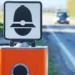 Autovelox installato sul bordo di una strada extraurbana mentre un'automobile si avvicina in lontananza, immagine simbolo delle nuove regole del Codice della Strada e delle sanzioni per eccesso di velocità