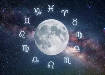 Un'immagine astronomica su un vasto sfondo di nebulose spaziali e galassie con la Via Lattea che forma una fascia colorata. Al centro c'è una Luna piena e luminosa, che risplende di luce. Attorno alla Luna, disposti in un cerchio segni zodiacali
